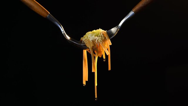 Cooked bigoli pasta twisted on fork with olive oil and parmesan