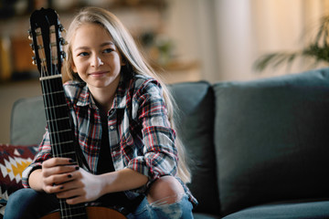Cute little girl playing guitar. Teenage girl learning to play guitar