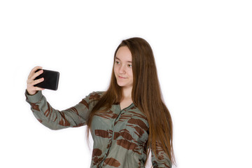 Naklejka premium Young girl 14 years old makes selfie with a smartphone on a white background
