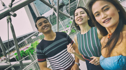 Fototapeta na wymiar Three asian friends enjoying outdoor city life, taking selfies. Friendship and holiday concept
