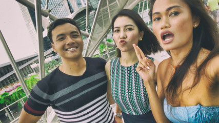Three asian friends enjoying outdoor city life, taking selfies. Friendship and holiday concept