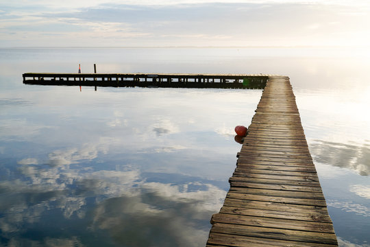wooden path access pontoon sunrise water reflection on Lake Hourtin in mirror image Gironde france