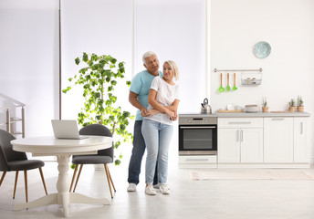Happy mature couple dancing together in kitchen
