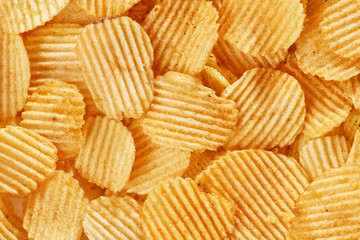 Potato grooved chips close up. Background of golden wavy corrugated chips  slices.