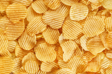 Potato grooved chips close up. Background of golden wavy corrugated chips  slices.