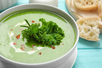 Tasty kale soup on light blue wooden table, closeup
