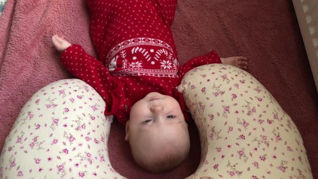 little cute adorable baby girl who wear christmas rompers  on the blanket and baby is looking to camera also she is making funny faces