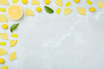 Flat lay composition with lemon drops on grey marble table. Space for text