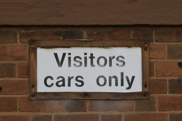 White 'Visitors Cars Only' Sign on Old Brick Wall
