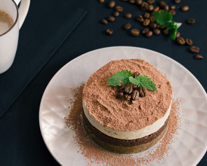 Tiramisu on a beige plate. Coffee with cinnamon. Raw dessert
