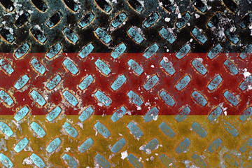 German flag with over steel diamond metal plate. Worn diamond plate surface with dirt and grit.