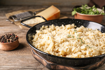 Delicious risotto with cheese on wooden table, closeup