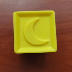 Yellow toy cube with moon on wooden background