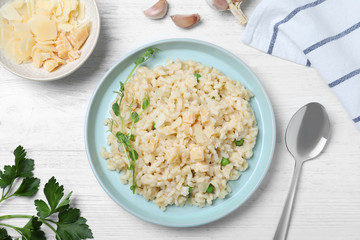 Delicious risotto with cheese on white wooden table, flat lay