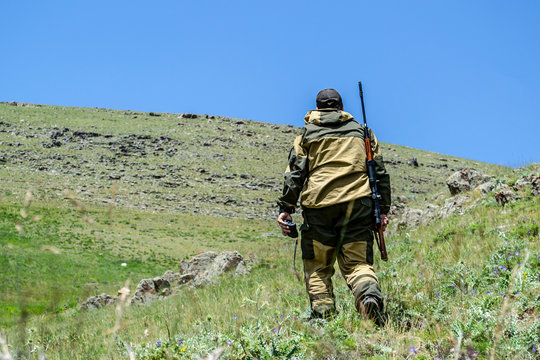 Hunter in the mountains with sniper rifle and laser distance meter.