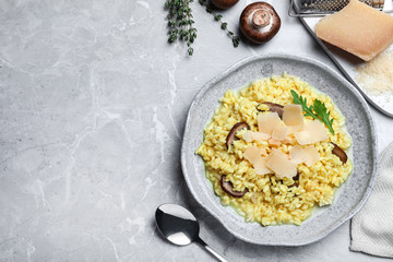 Delicious risotto with cheese and mushrooms on grey marble table, flat lay. Space for text