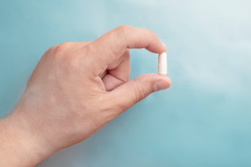 Hand holding white pill on blue background, great design for any purposes. Health care medical background. Medicine, healthcare concept. Pharmacy concept. Medicine pill.