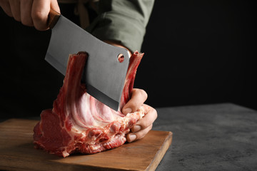 Man cutting raw ribs at grey table, closeup. Space for text