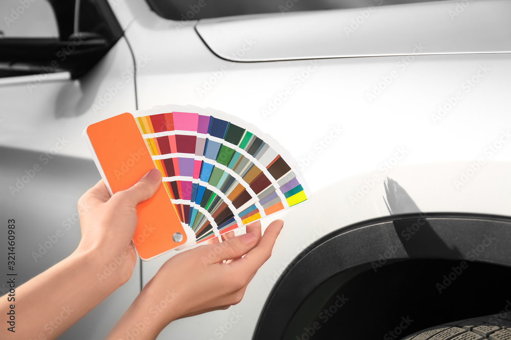 Poster Woman with palette samples choosing color for painting car, closeup