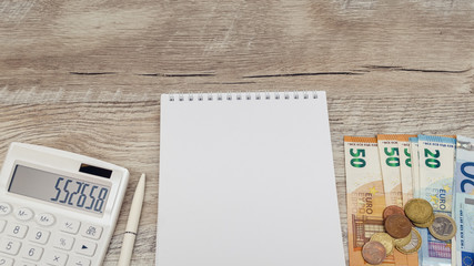 Workplace. Calculator, pen, notebook and money on the table. White background