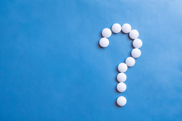 Question mark white pills on blue background. Medicine science. Cure concept. Question mark icon. Medicine pill.