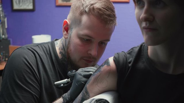 Footage of young tattooer getting tattoo of snake in salon, process