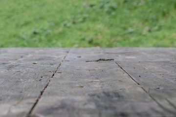 Wooden table in perspective with green grass background, selective focus.