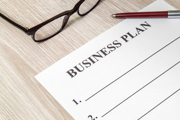 Blank form and pen for drawing up business plan on table