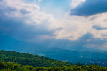 Summer landscape of foothils with scenic sky with sunrays.