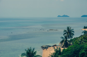 Top view of empty tropical white sandy beach, blue clear water of sea and palm trees, nobody on the beach