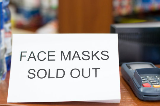Information plate on counter in pharmacy with text: face masks are sold out, not in stock. Epidemic of N-CoV 2019 influenza coronavirus mutated and spreading in China. Bank card payment terminal