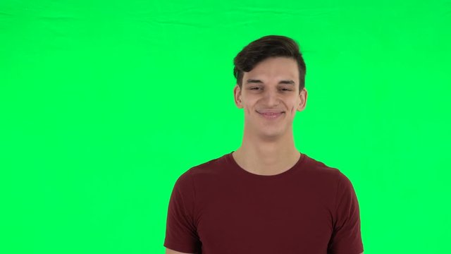 Guy smiling while looking at camera. Green screen