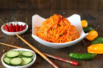 Carrot Korean meat salad with chopsticks on wooden oak table