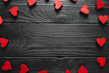 Valentines Day frame of wooden heart decorations. Top view against a rustic dark wood background.