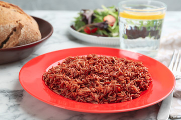 Tasty brown rice served on white marble table