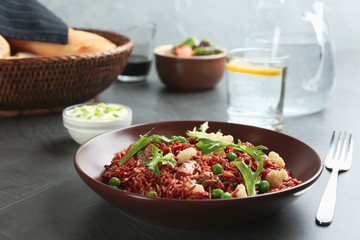 Tasty brown rice with meat and vegetables served on dark grey table