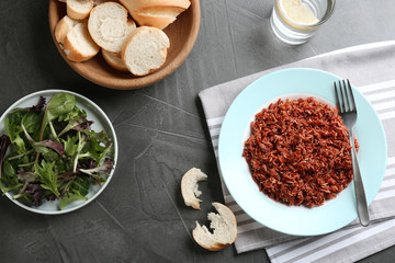 Tasty brown rice served on dark grey table, flat lay