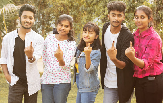 Group of teenager friends showing ink marked fingers outside polling station or booth after casting votes - Concept of Indian election or vote casting system.