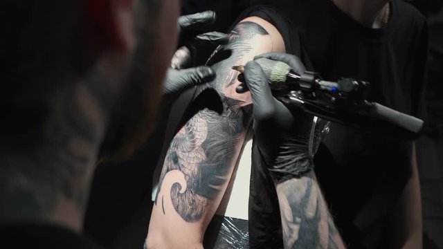 Video of doing black tattoo of snake on woman in studio