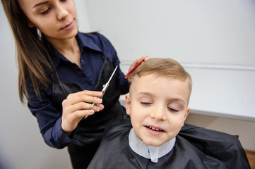 Close up picture of boy/child kid, sitting in the hairdressing salon