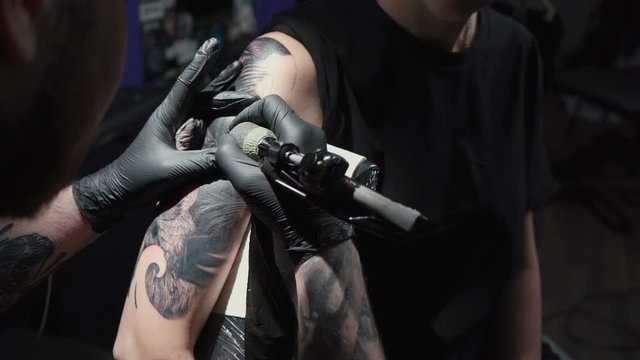 Video of man doing tattoo of snake on woman in studio