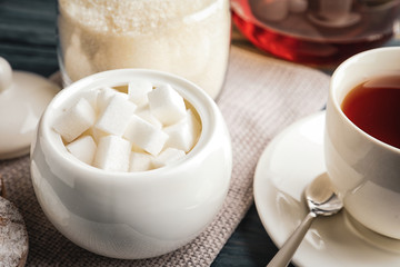 Refined sugar cubes in ceramic bowl on table