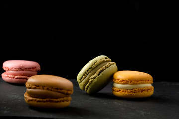 delicious chocolate and vanilla Macarons over wooden board on dark background with space for text