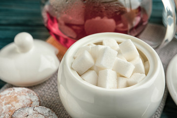 Refined sugar cubes in ceramic bowl on table, closeup
