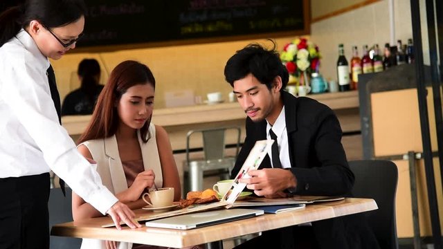 Couple lover order food to waitress in restaurant on 14 feb valentine's day. Waitress note food order from customer look at menu has service mind with smiling face. Valentine's day concept.
