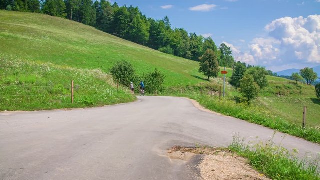 Cyclists on Path Through Scenic European Landscape in Slovenia, Pan L to R
