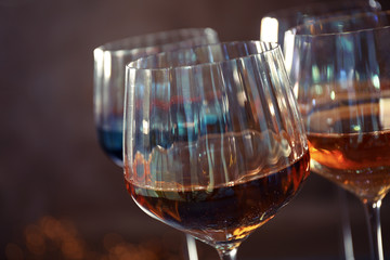 Elegant glasses with different wines on brown background, closeup
