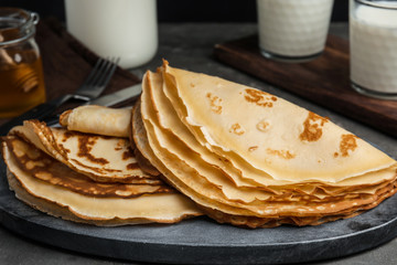 Fresh thin pancakes on grey board, closeup