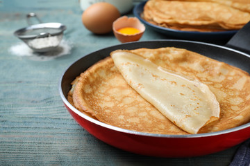 Delicious thin pancakes on blue wooden table, closeup