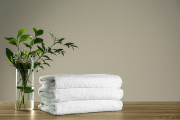 Obraz na płótnie Canvas Clean bath towels and vase with green plants on wooden table. Space for text